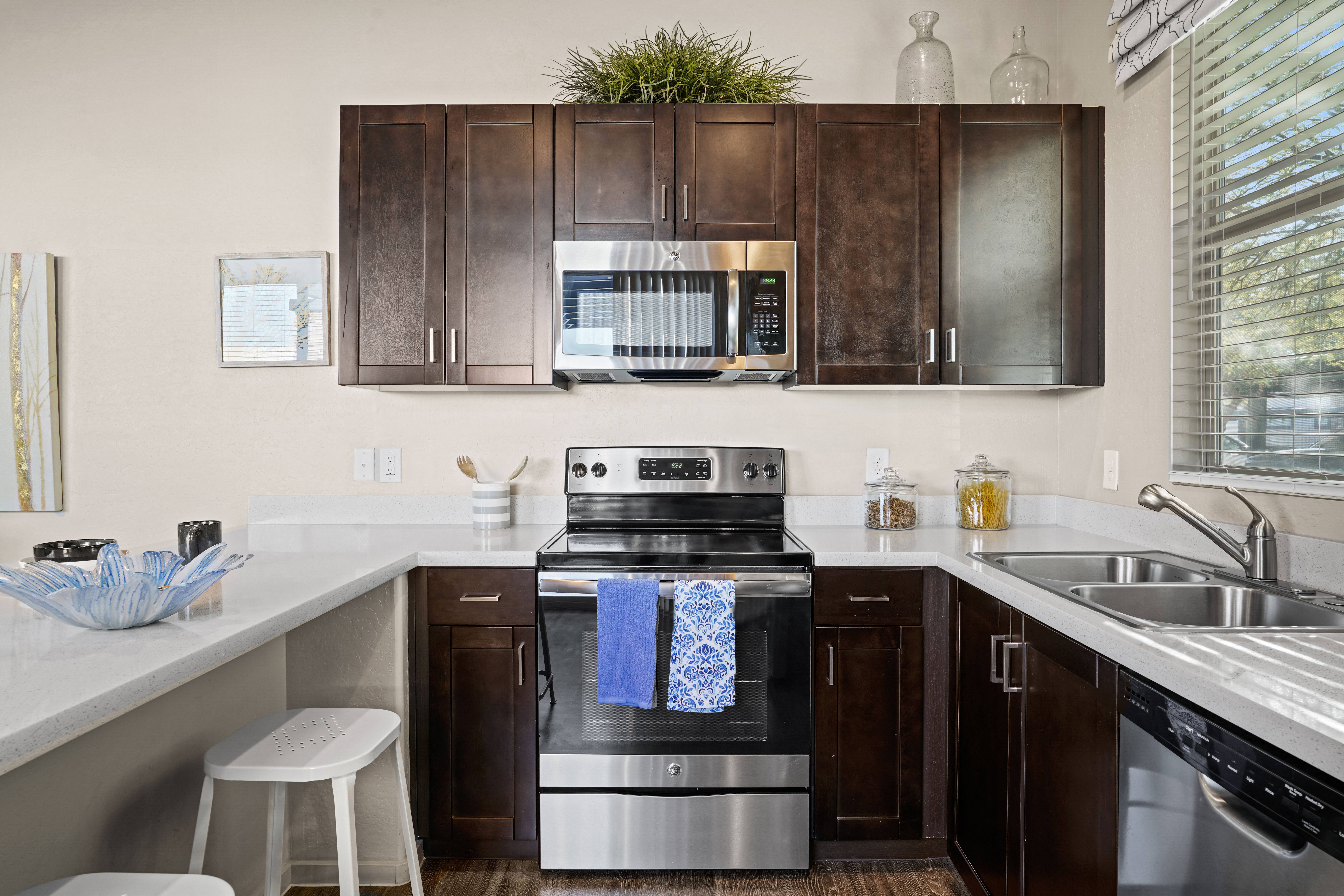 a kitchen with stainless steel appliances and dark wood cabinets at Olive Queen Creek Apartments, Queen Creek, 85142